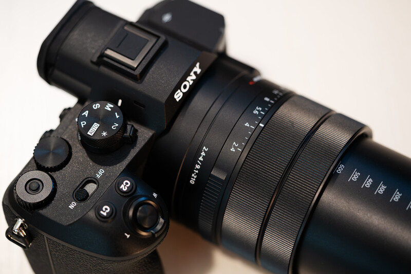 Sony mirrorless camera with attached zoom lens viewed from above on neutral background