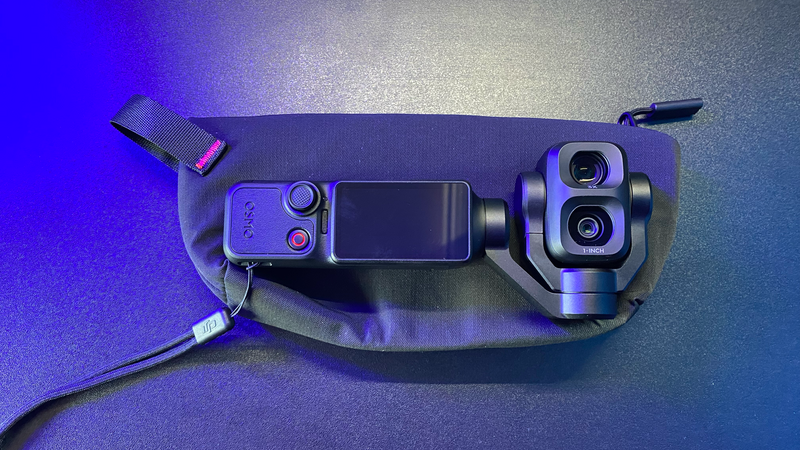 DJI Osmo Mobile gimbal with smartphone mounted between dual camera modules, displayed against blue and purple gradient lighting
