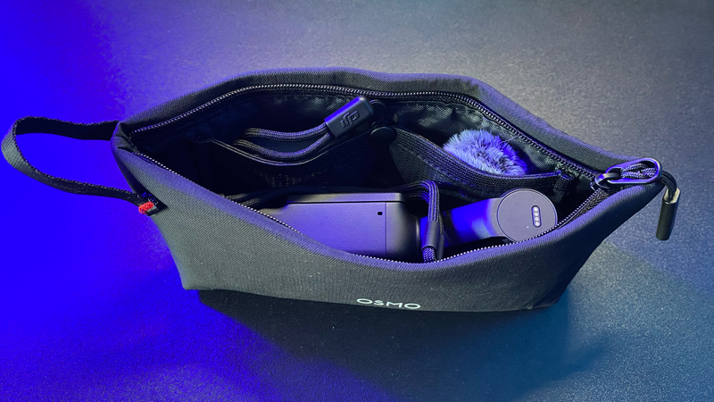Open camera bag displaying internal organization with phone, accessories, and storage compartments under blue studio lighting