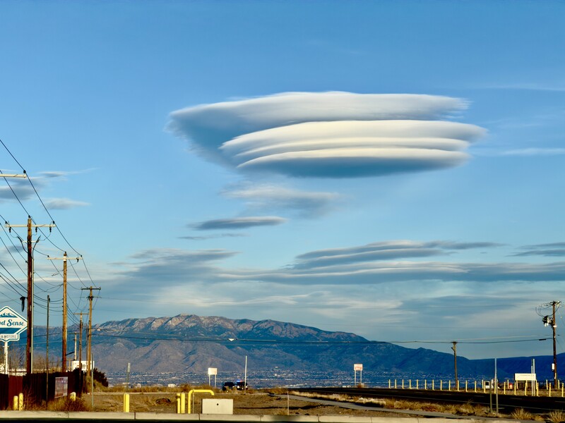 Lenticular clouds stacked in UFO-like formation above desert mountains