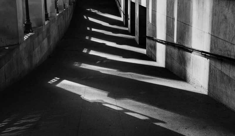Striped shadows cast through corridor windows onto concrete floor
