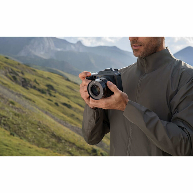 Photographer holding compact binoculars in mountainous landscape