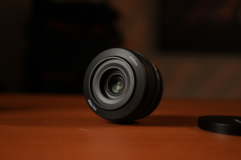 Black prime lens with multi-coated glass elements displayed on wooden surface
