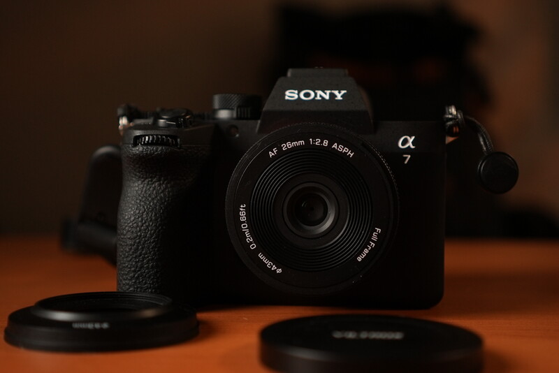 Sony a7 mirrorless camera with 35mm lens on wooden surface with lens caps