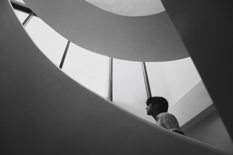 Silhouetted figure standing inside a geometric spiral structure with dramatic overhead lighting