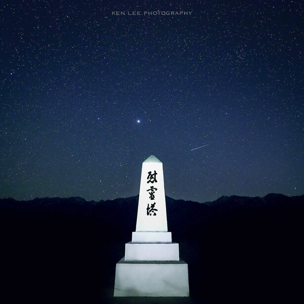 White stone monument with Japanese characters silhouetted against a starry night sky