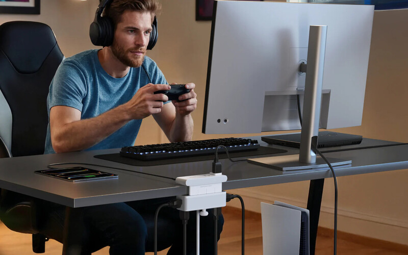 Man wearing headphones playing video game with controller at desk setup
