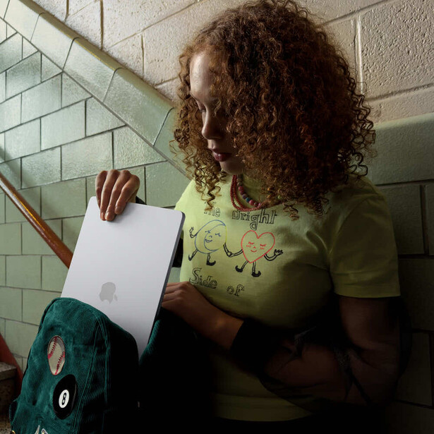Person with curly hair wearing lime green shirt holding white paper near tiled wall