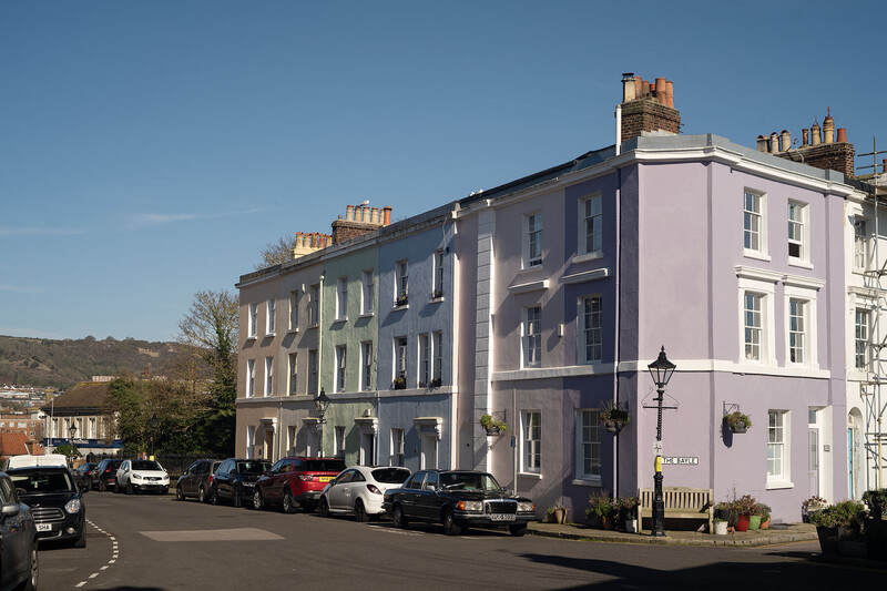 Row of colorful Georgian terraced buildings with parked cars on street