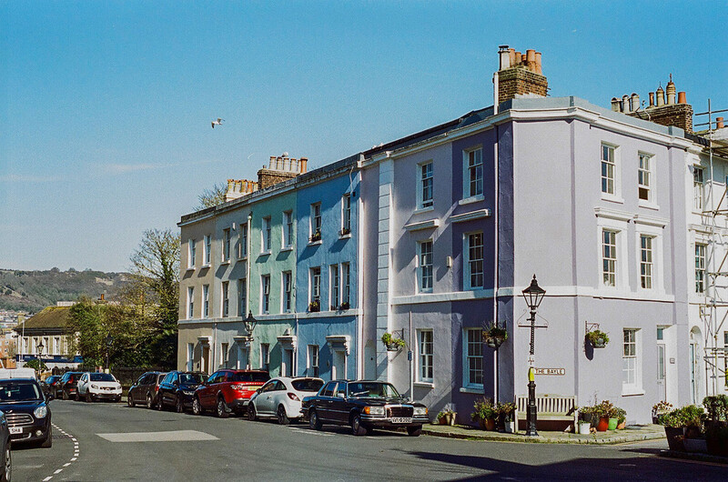 Colorful Victorian townhouses with parked cars on a residential street