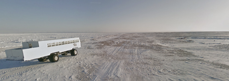 White livestock trailer on frozen beach with ice formations and ocean horizon
