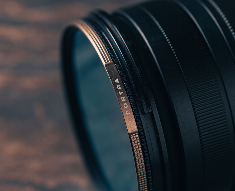 Close-up of a camera lens with stacked filter rings and glass elements visible