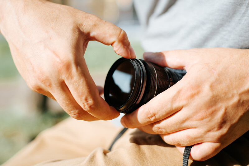 Photographer's hands holding a wide-angle lens with focus ring visible