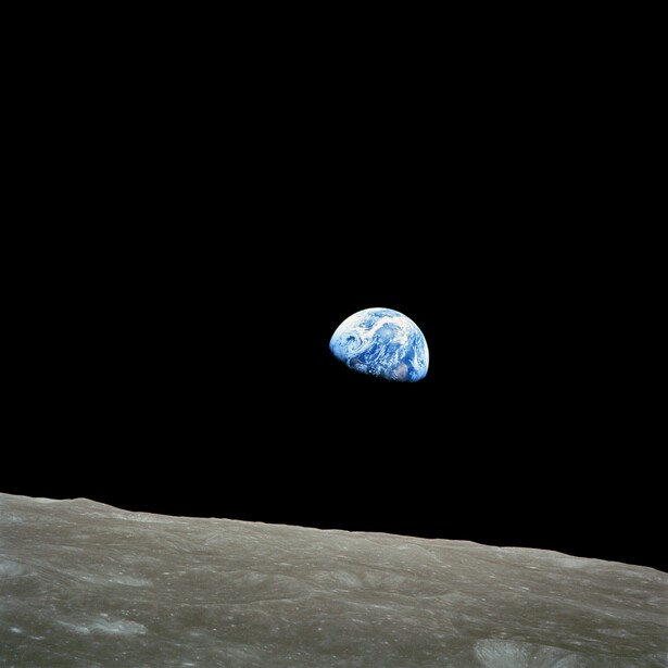 Earth rising above the lunar horizon against black space