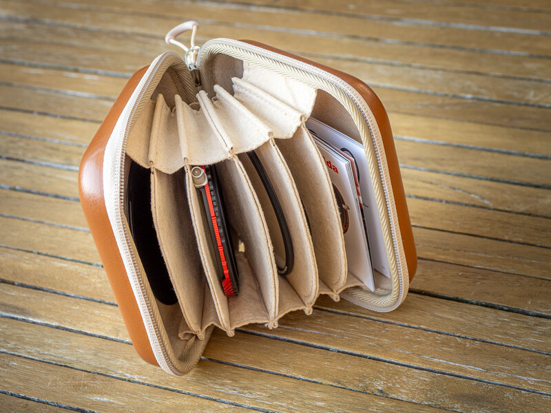 Orange accordion-style wallet with cream-colored accordion dividers displaying organized compartments on wooden floor