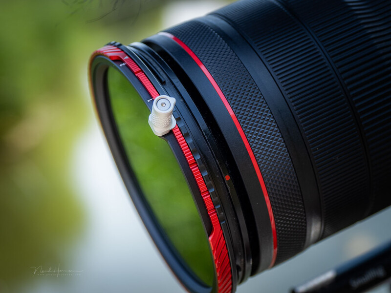 Red focus ring and red accent line on telephoto lens with blurred green background