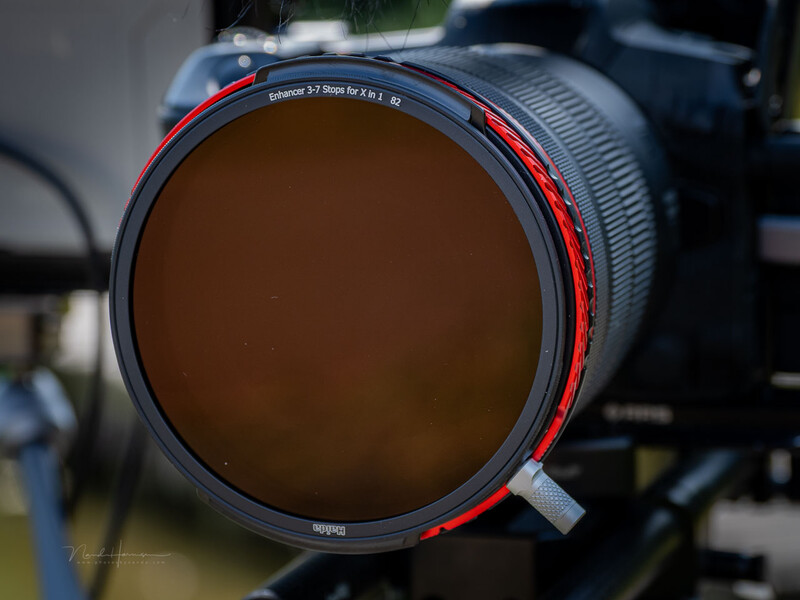 Large diameter circular ND filter with red-tinted rim mounted on camera lens