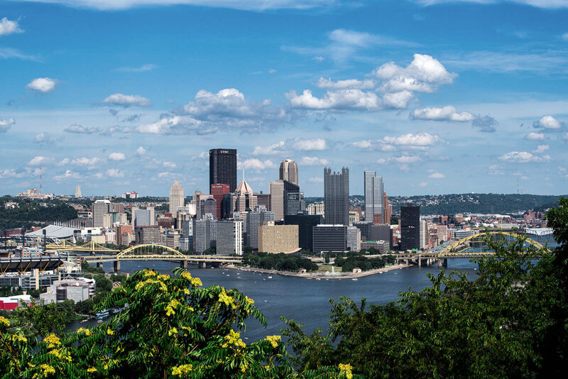 Pittsburgh skyline with golden hour lighting and blue sky with white clouds