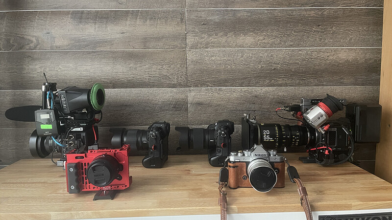 Collection of cinema cameras and filmmaking equipment arranged on wooden surface