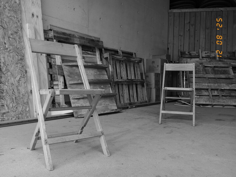 Wooden ladder leaning against wall in sparse industrial space with stacked wooden crates