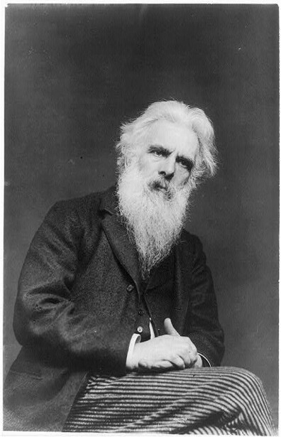 Black and white portrait photograph of an elderly man with long white beard wearing dark clothing