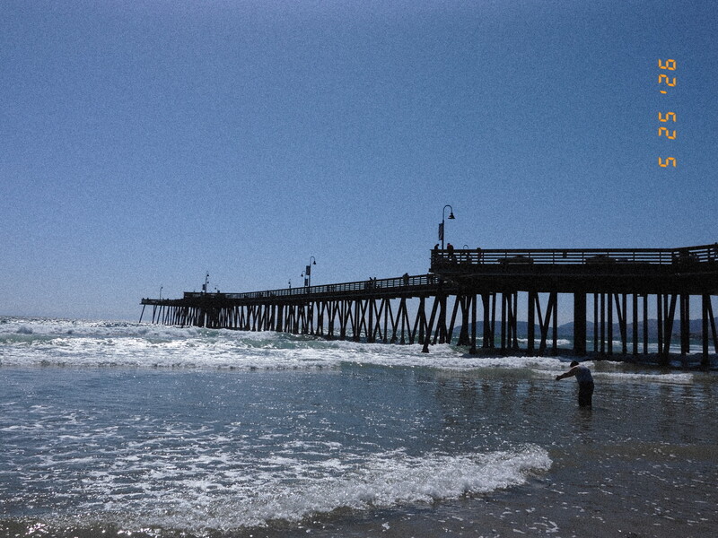 Wooden pier extending into ocean waves under clear blue sky
