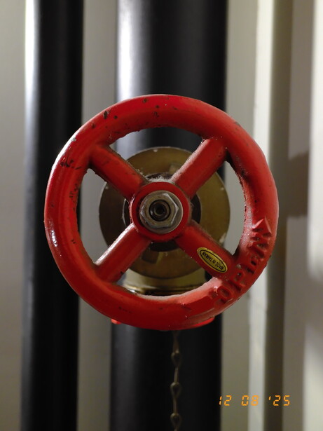 Red industrial valve wheel mounted on metallic cylindrical pipe