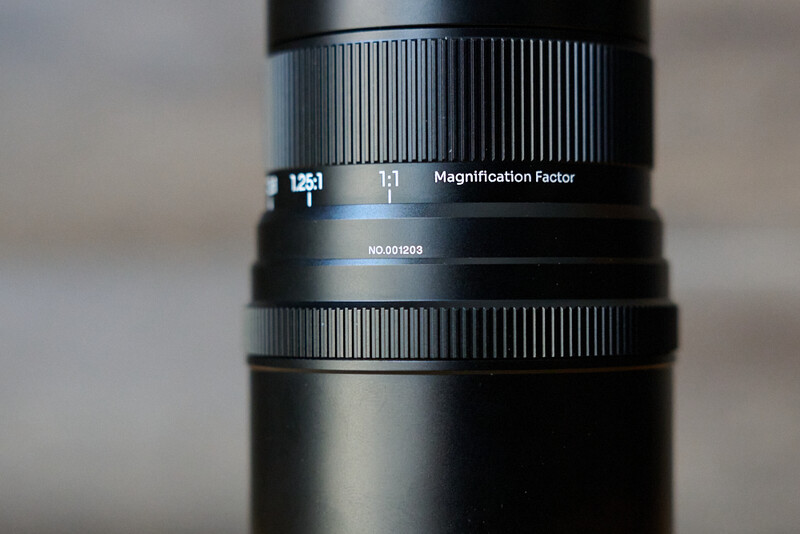 Close-up of a telephoto lens showing magnification factor dial and serial number marking