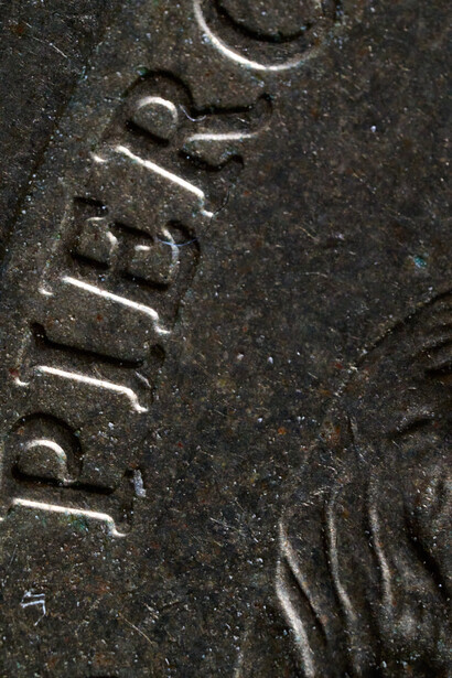 Close-up of embossed or cast text reading "FUJIFILM" on a dark textured metal surface