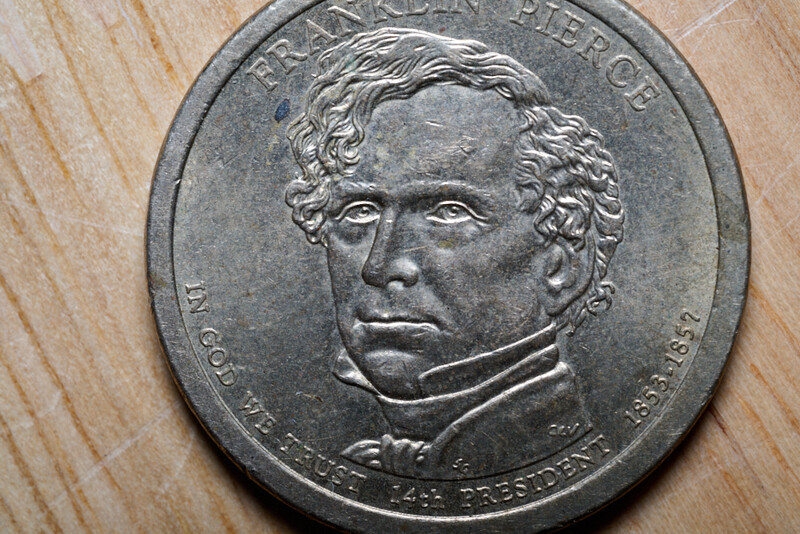 Close-up photograph of a U.S. presidential dollar coin showing a portrait in profile relief