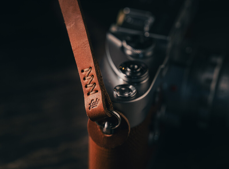 Leather camera strap with embossed text attached to vintage rangefinder camera