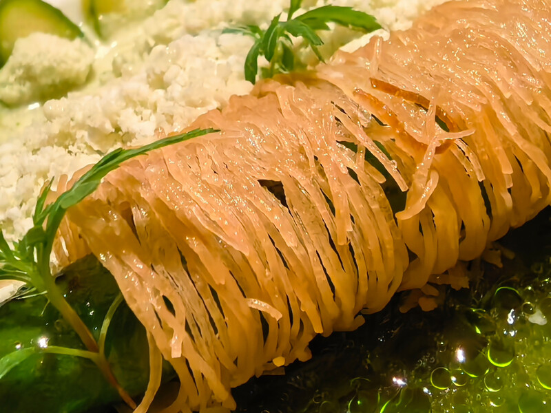 Sliced smoked salmon with herb garnish and microgreens on dark plate