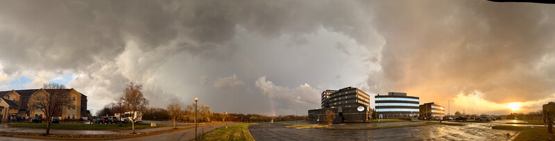 Dramatic sunset sky over suburban commercial development with puffy clouds and golden light