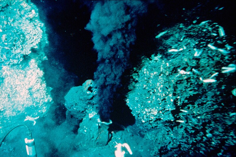 Deep-sea hydrothermal vent with turquoise mineral deposits and plume