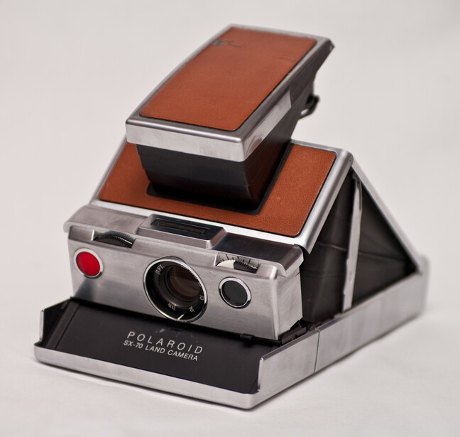 Polaroid SX-70 instant camera with brown leather case and flash attachment stacked vertically