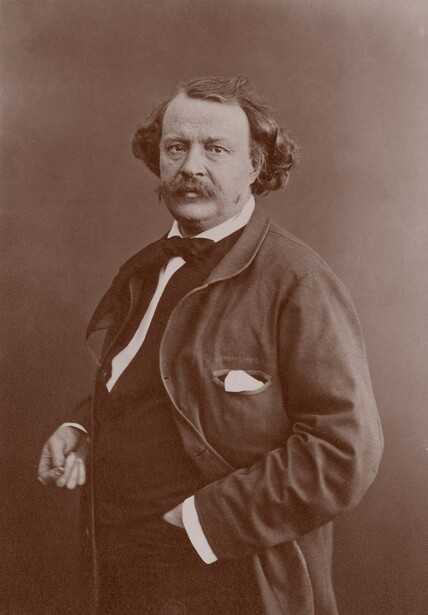Sepia-toned studio portrait of a bearded man in Victorian-era formal attire with cane
