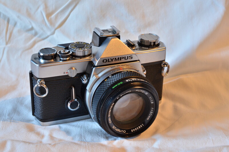 Olympus OM-1 film camera with Zuiko lens on white fabric background