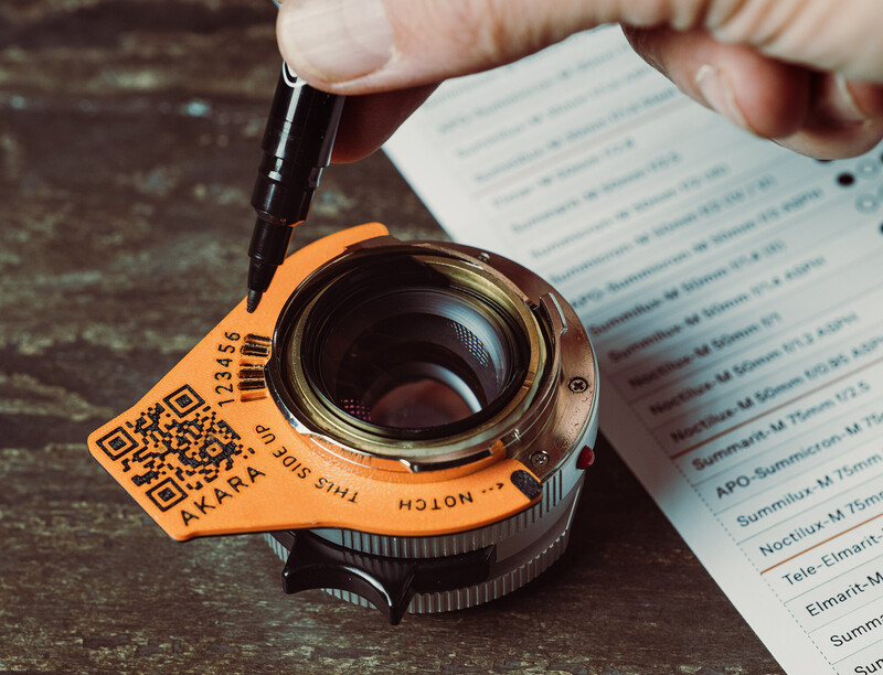 Vintage camera lens with orange lens cap and QR code being held over photography documentation