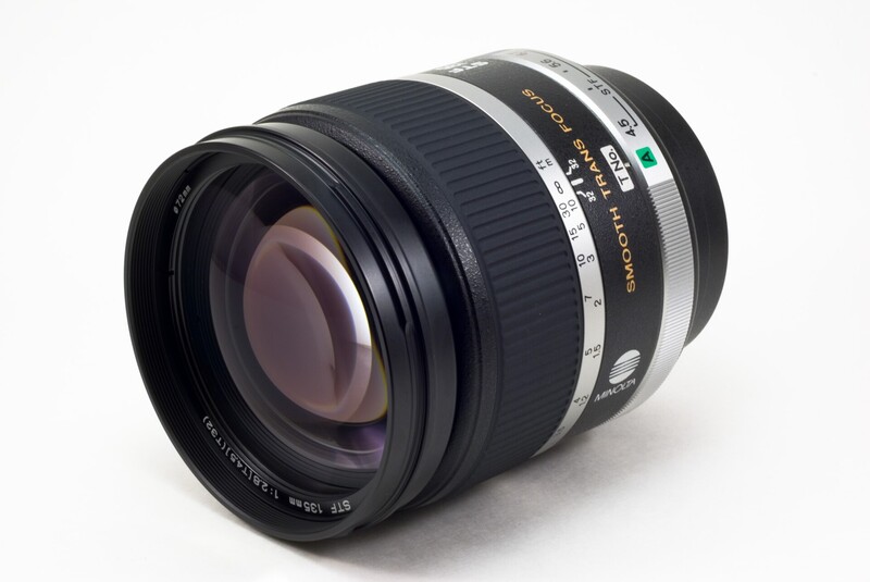 Telephoto prime lens with black barrel and silver focus ring on white background