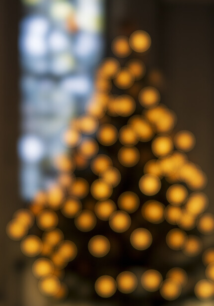 Blurred golden ornaments arranged in tree form with wrapped gift box in background