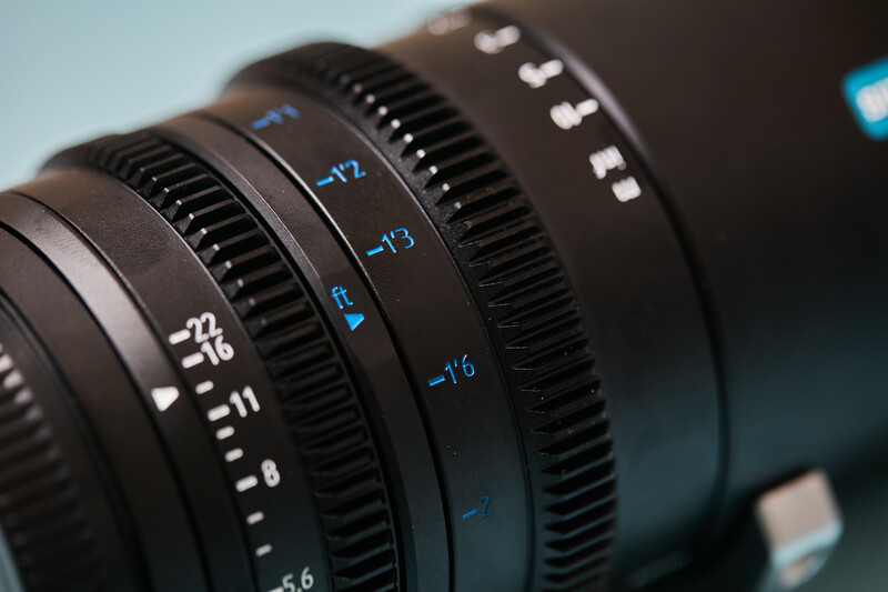 Close-up of cinema lens barrels showing focus and aperture markings with blue text indicators