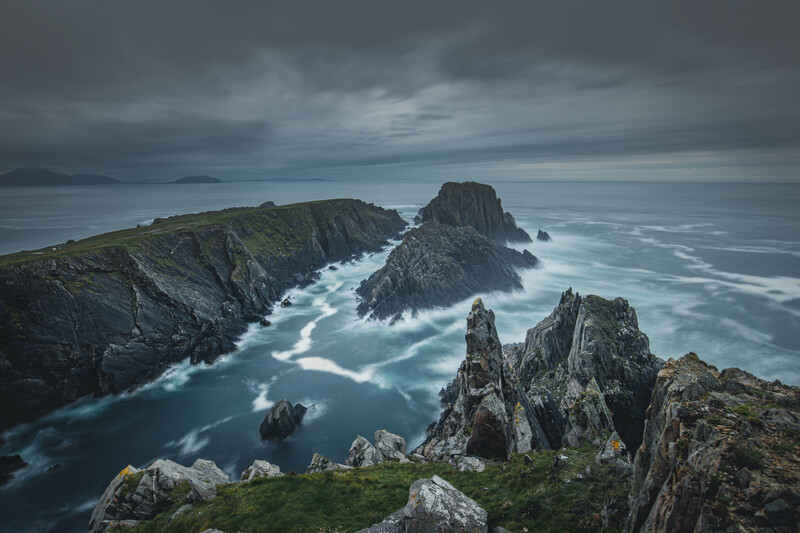 Dramatic rocky coastal headland with jagged sea stacks and moody storm clouds