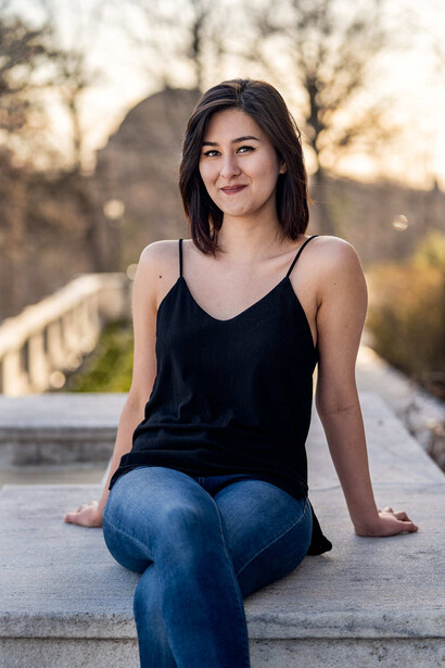 Woman in black camisole and jeans seated on concrete steps during golden hour