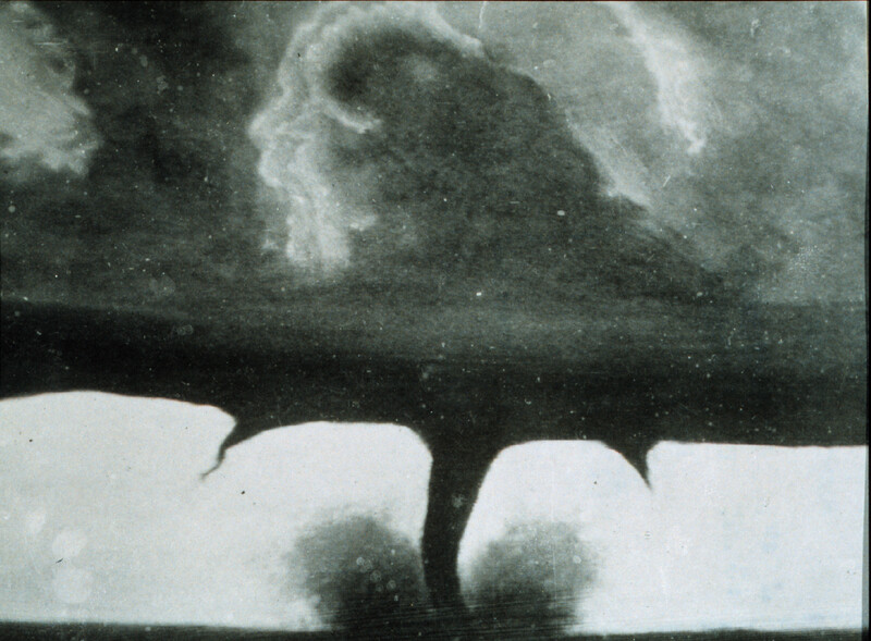 Vintage black and white footage of multiple tornadoes touching down across a flat landscape