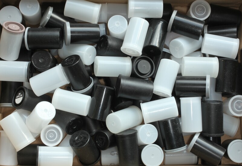Assorted white and black plastic film canisters and caps scattered overhead