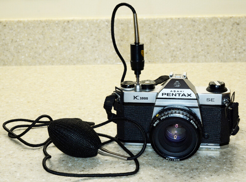A squeeze-bulb shutter release, hose and all, screwed into the shutter button of a Pentax K1000 SE