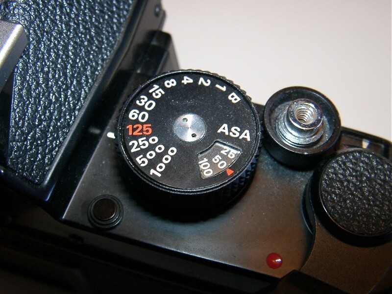 A film SLR shutter speed dial running B, 1, 2, 4, 8, 15, 30, 60, 125, 250, 500, 1000, with the ASA film speed window set into the same dial
