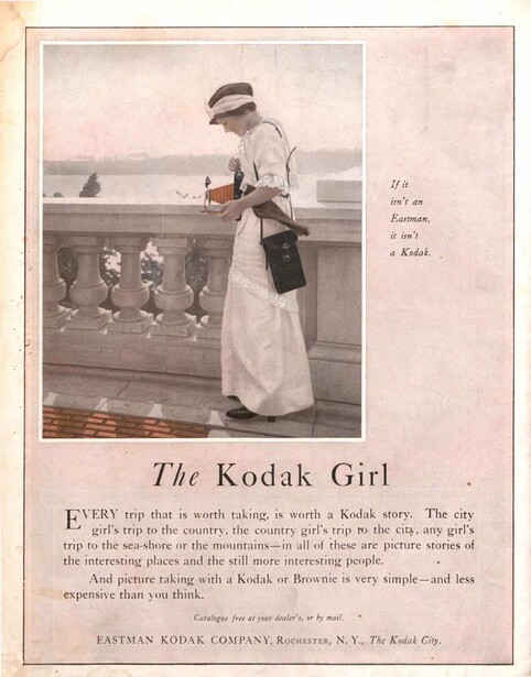 Woman in early 1900s dress standing at ship railing with camera, titled 'The Kodak Girl'