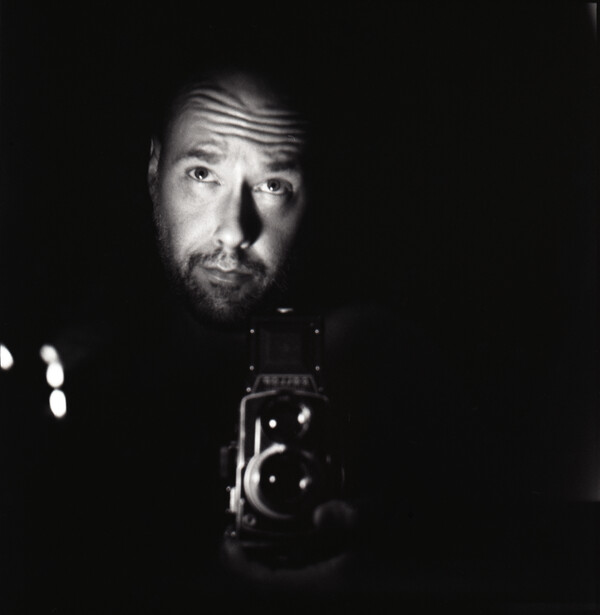 Man holding vintage film camera in dramatic low-key lighting
