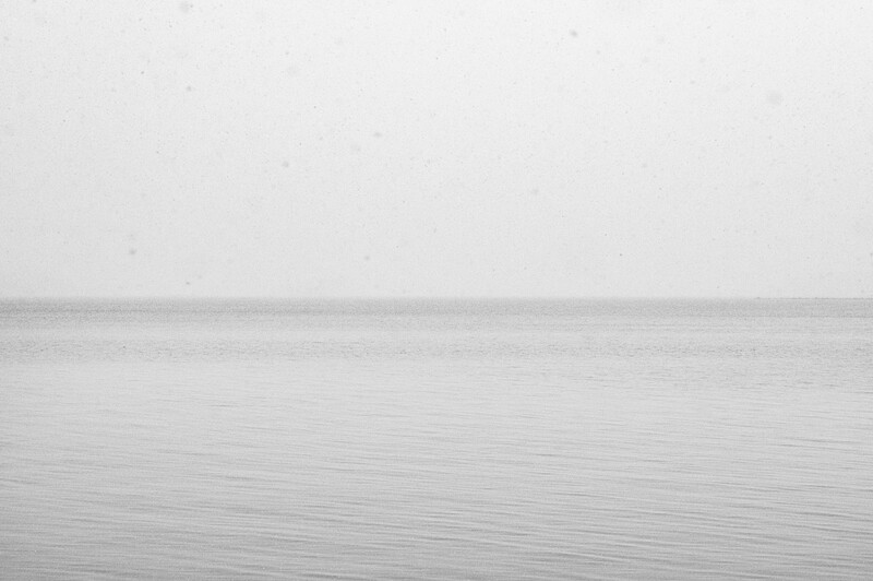 Minimalist seascape with calm water and overcast sky meeting at horizon
